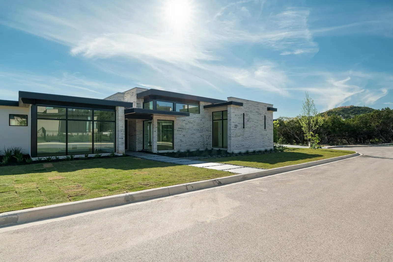 Modern stone house with large windows under a bright sky